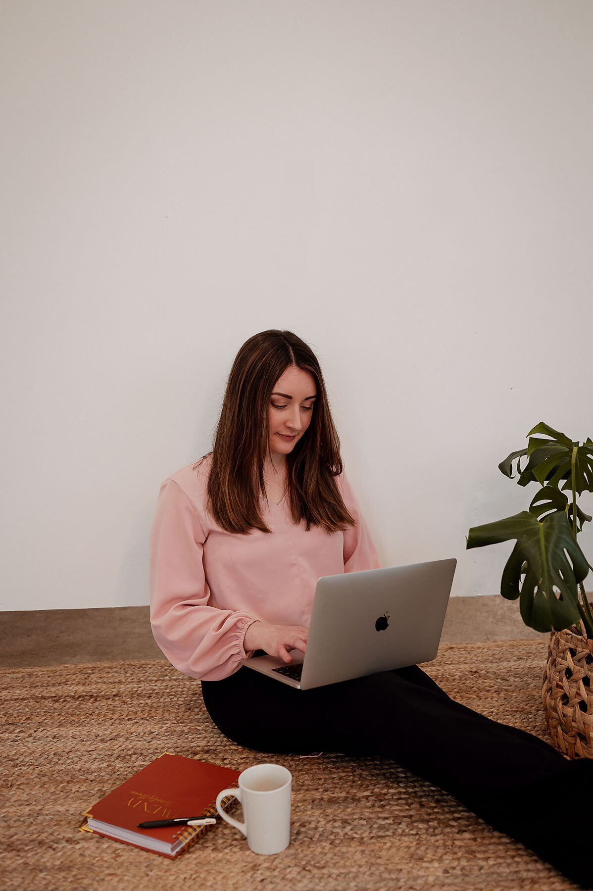 Lifestyle portrait of woman sitting on ground typing on laptop