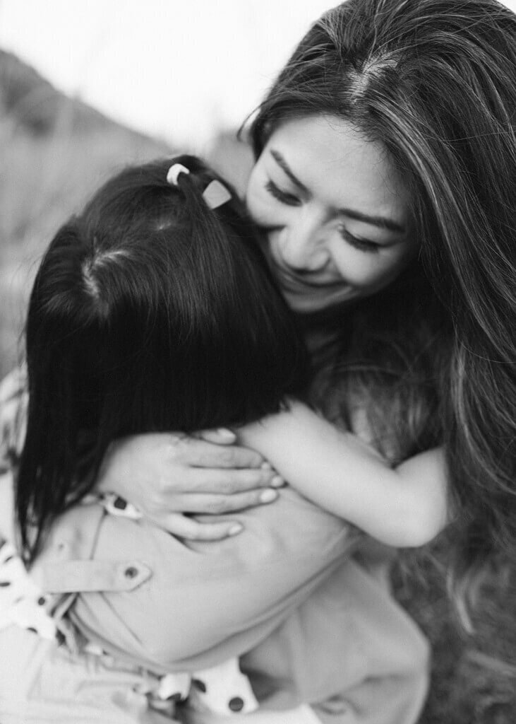 black and white photo close up shot of a mommy and daughter hugging each other.