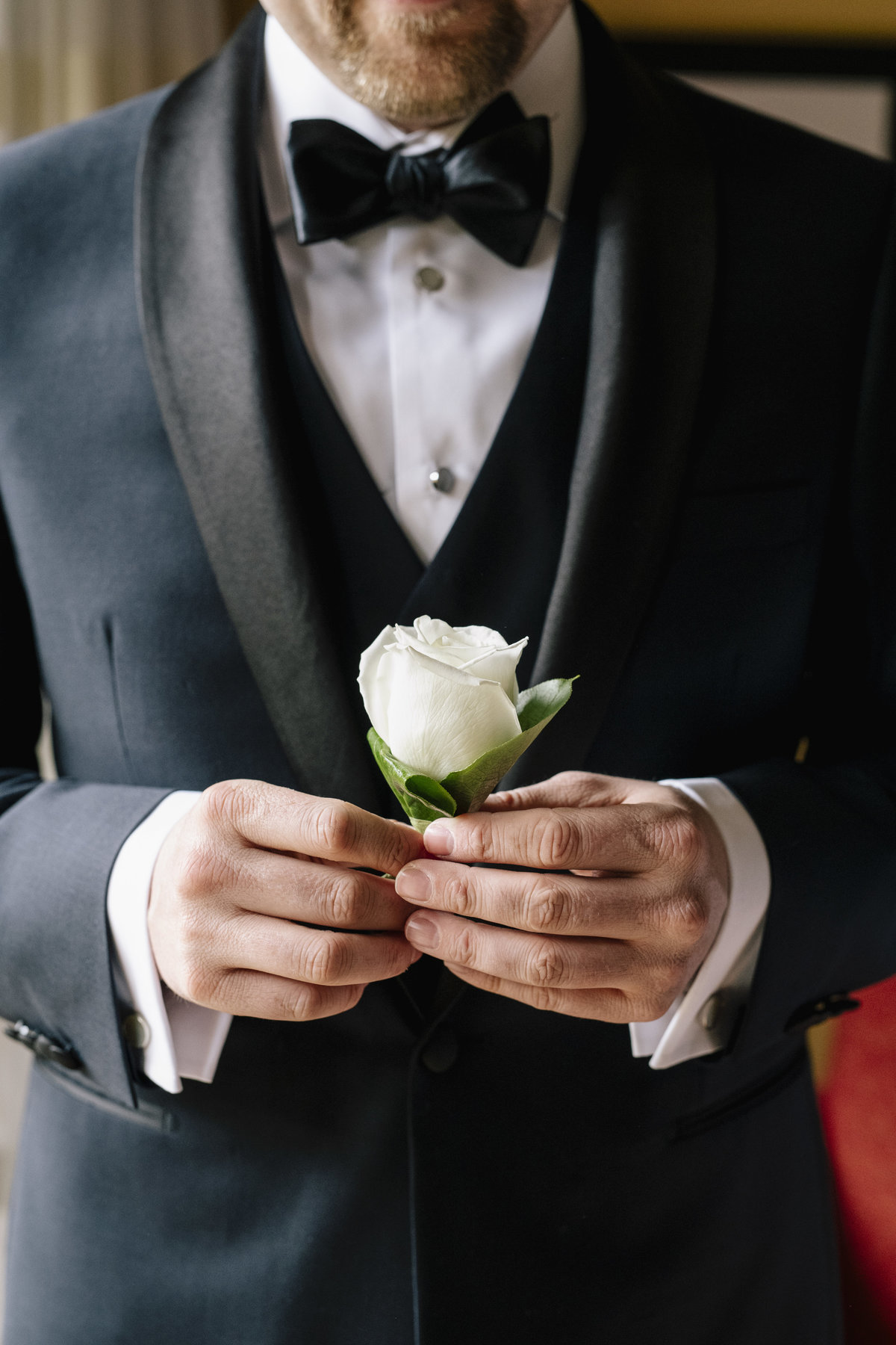 groom holding his boutonniere before wedding