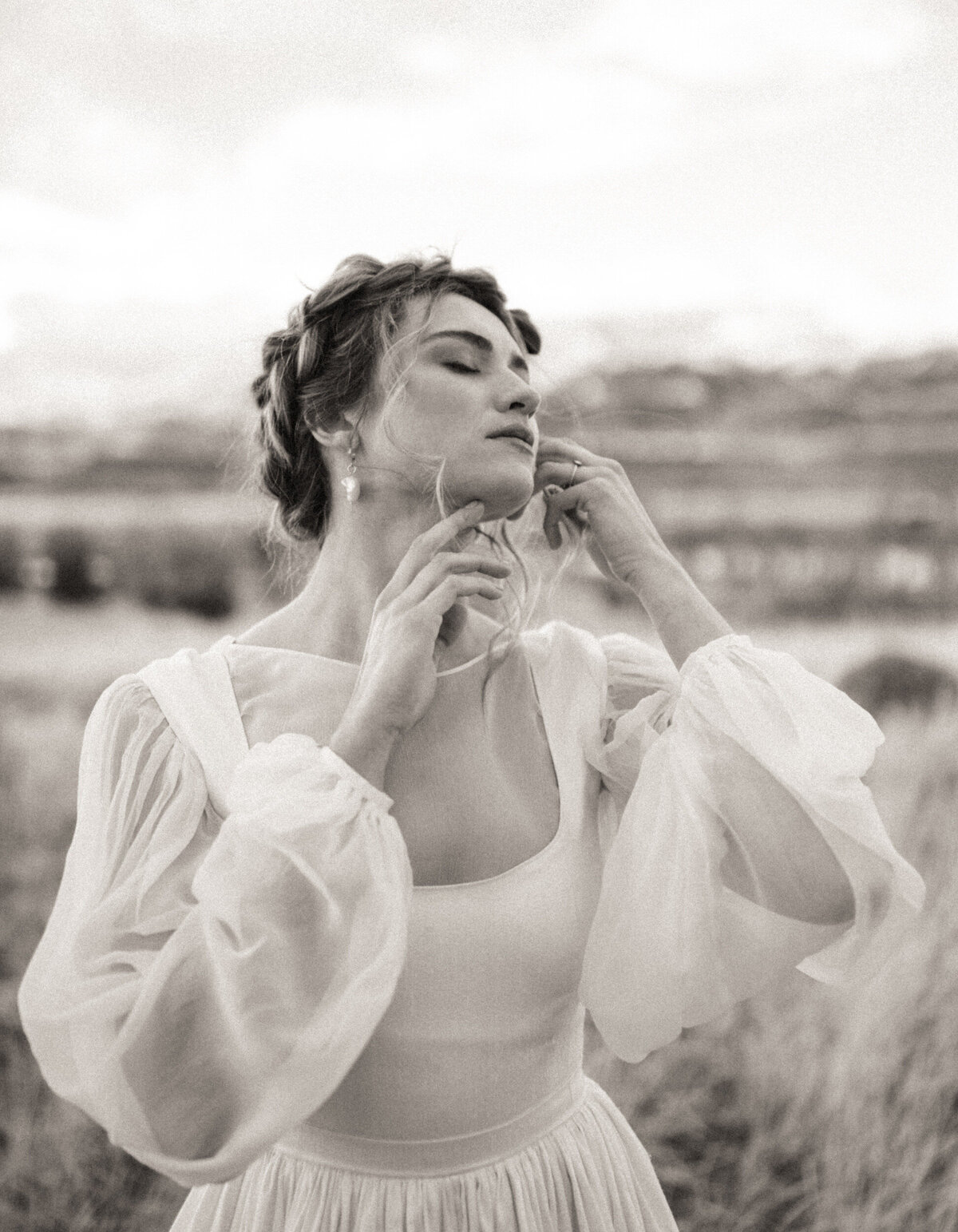 Bride with boho braided updo and puffy sleeves poses in wedding dress