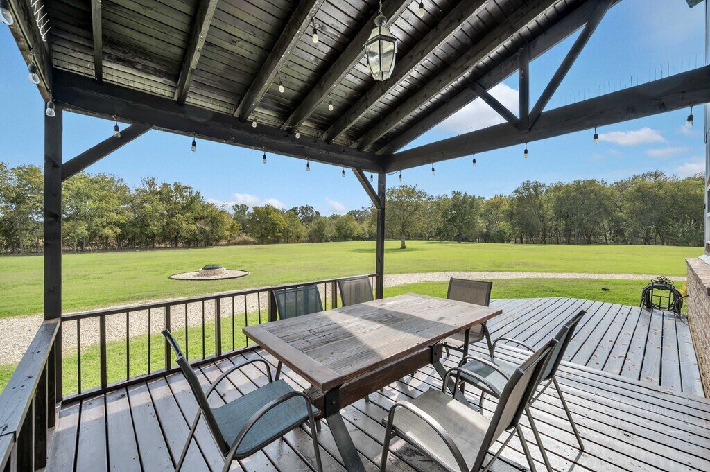 Covered deck with table for six and a beautiful view at this four-bedroom, four-bathroom vacation rental home and guest house with free WiFi, fully equipped kitchen, firepit and room for 10 in Waco, TX.