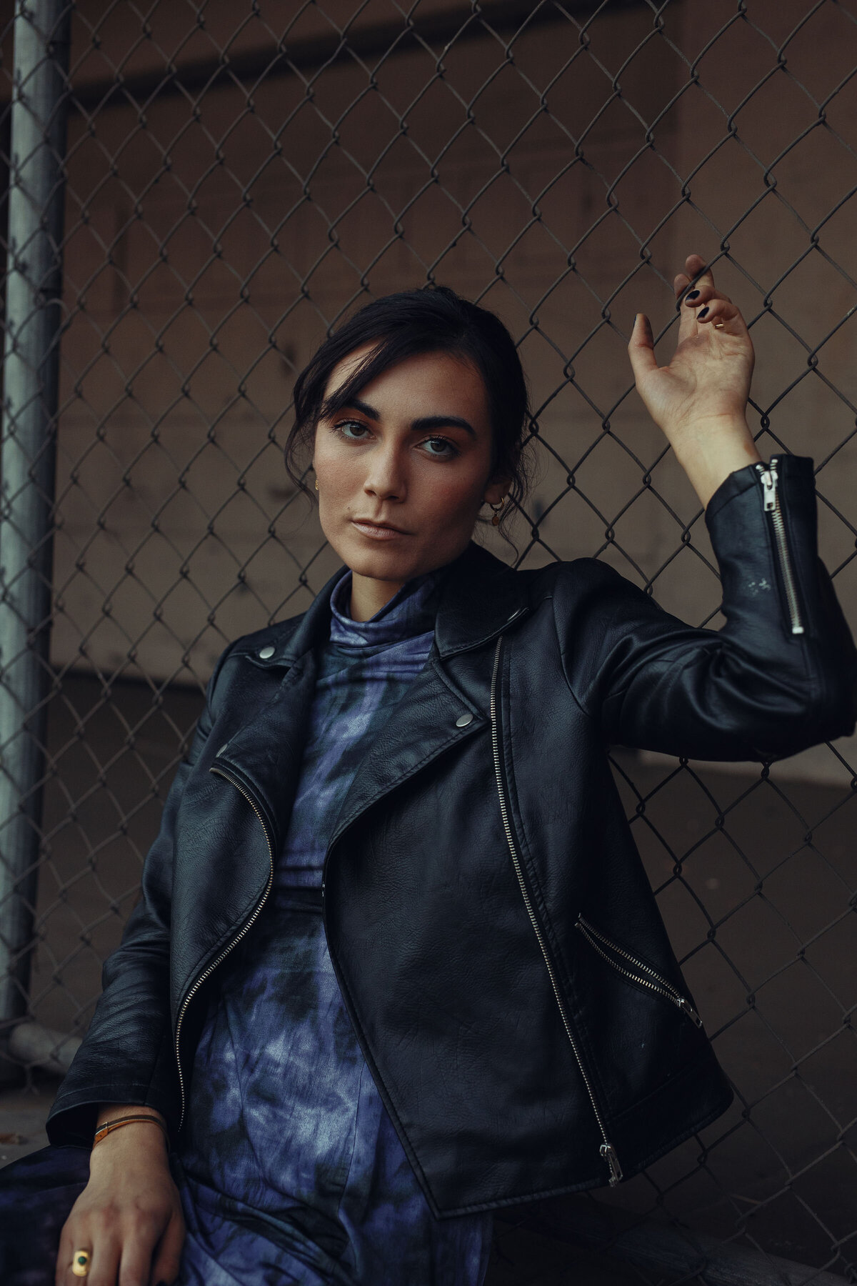 Portrait Photo Of Young Woman In Black Leather Jacket Leaning Against a Screen Gate Los Angeles
