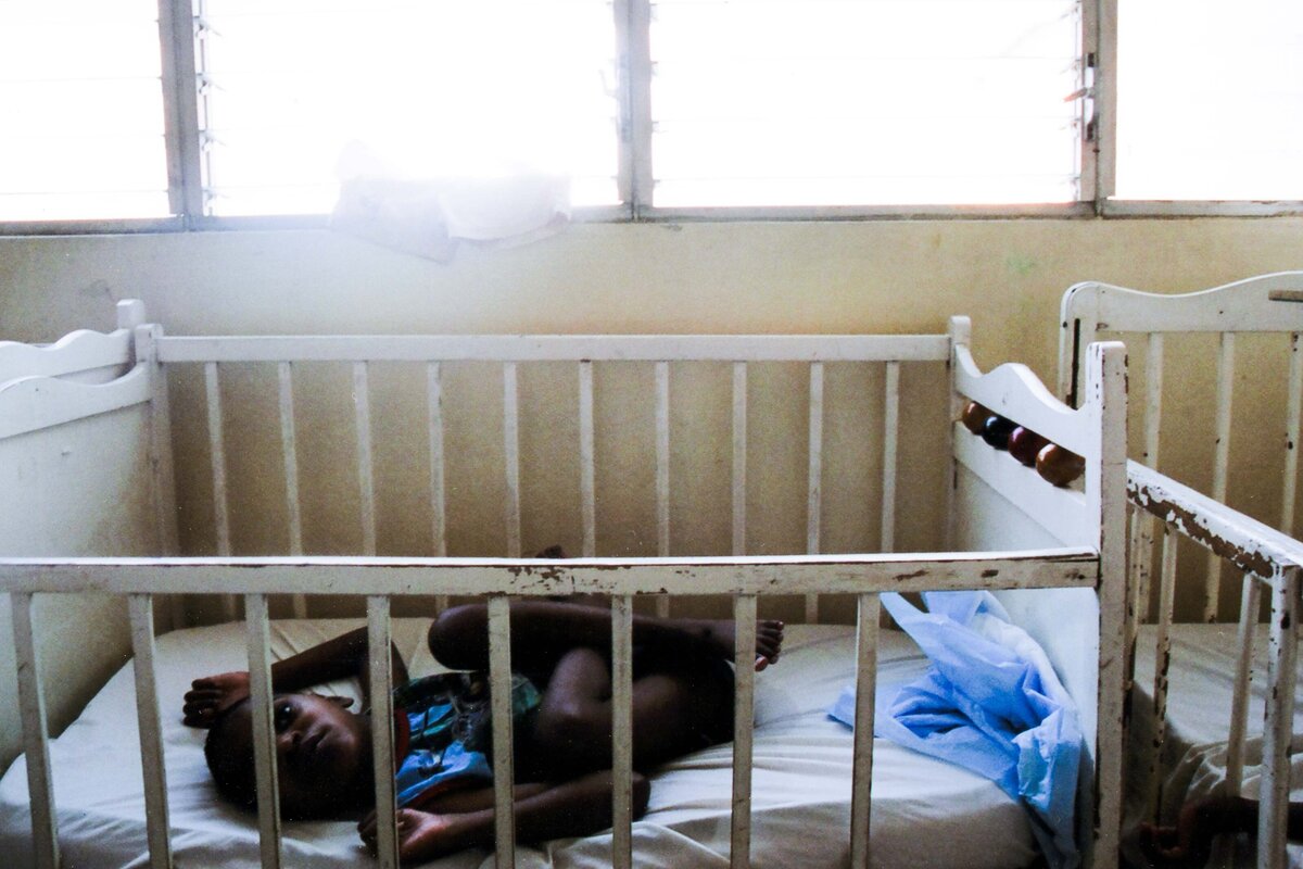 Child lays in crib that is too small for him at orphanage of children with disabilities
