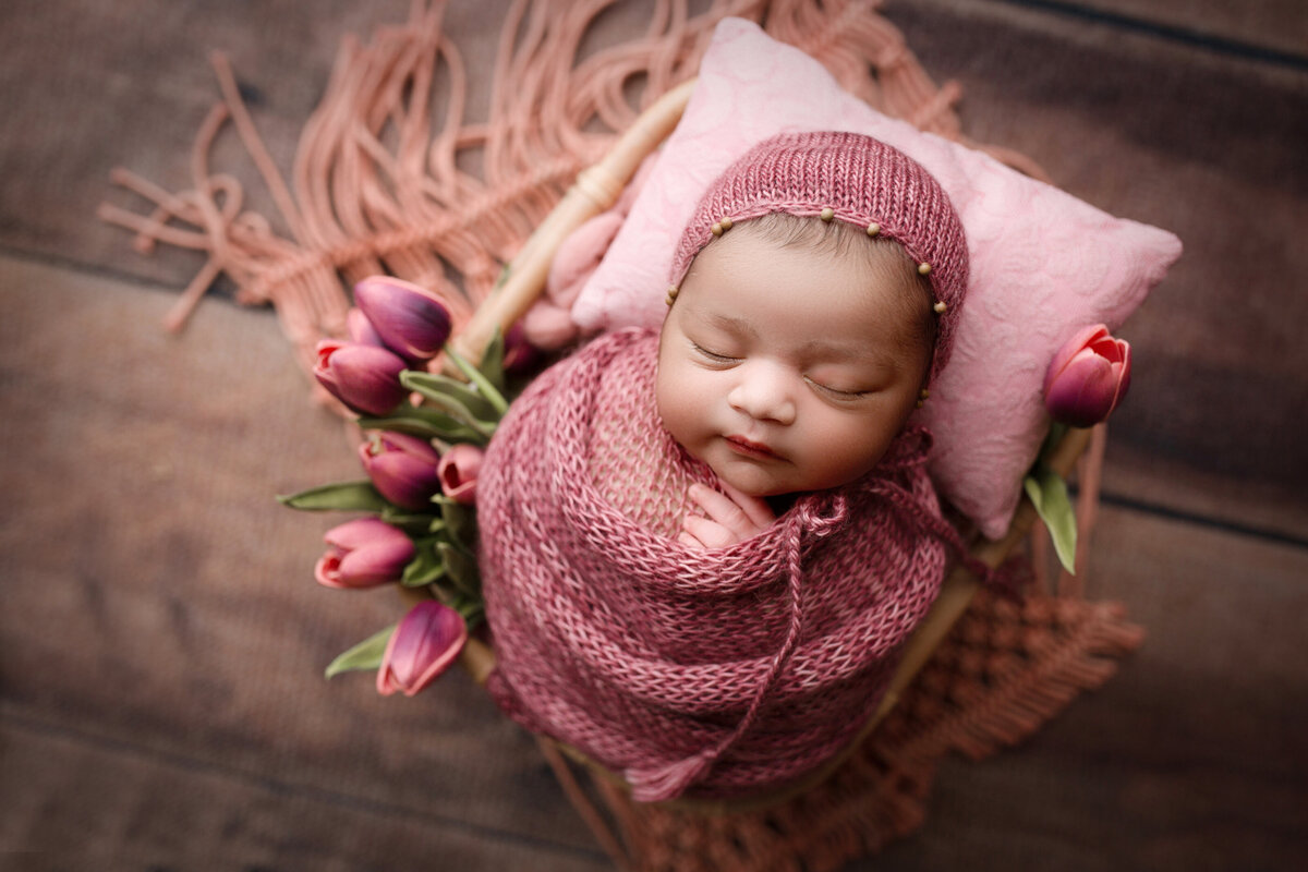 baby girl in a dark pink wrap and bonnet with purple tulips
