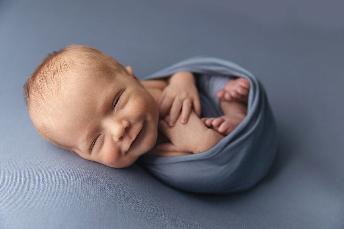 Newborn baby sleeping  posed with a smile in Westmoreland county.