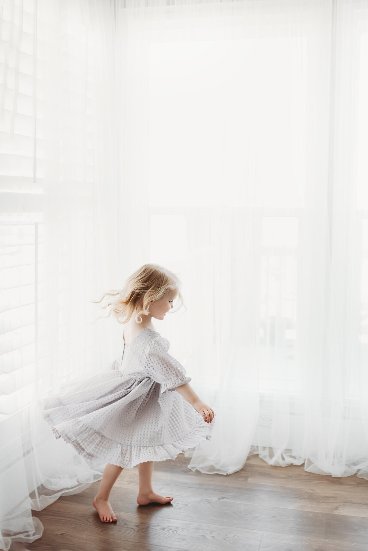 girl twirling in big room of windows in Alyssum Hutchison photo studio