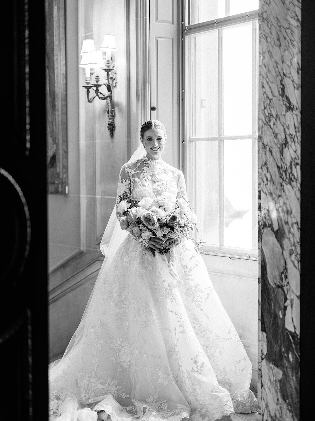A black and white portrait of a cride through the door at the wedding venue.