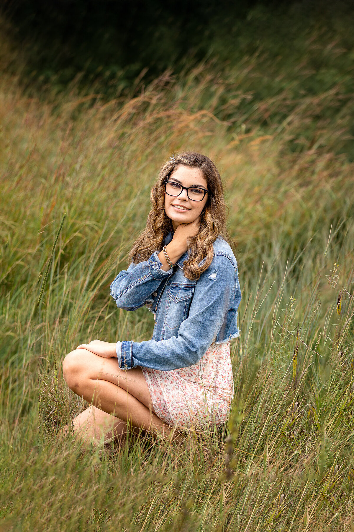 Girl poses in tall grasses for her senior picture session in Minnesota.