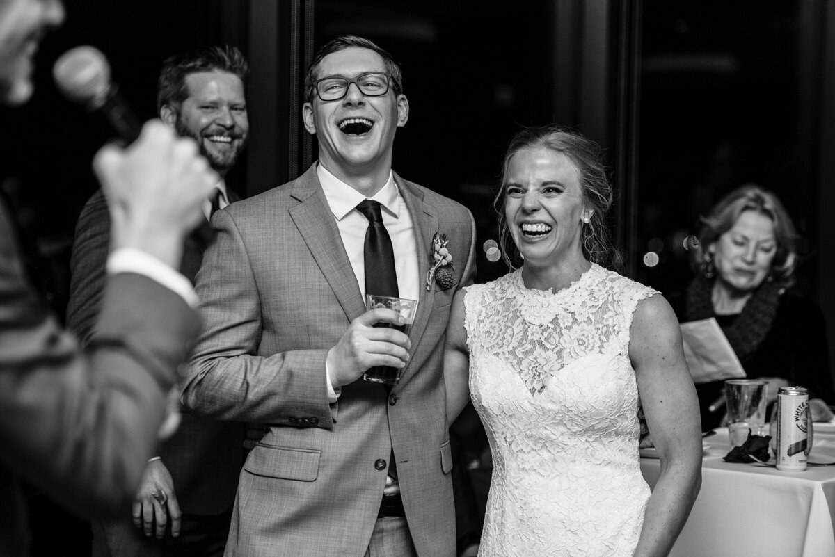 Bride and groom laugh during wedding speeches.