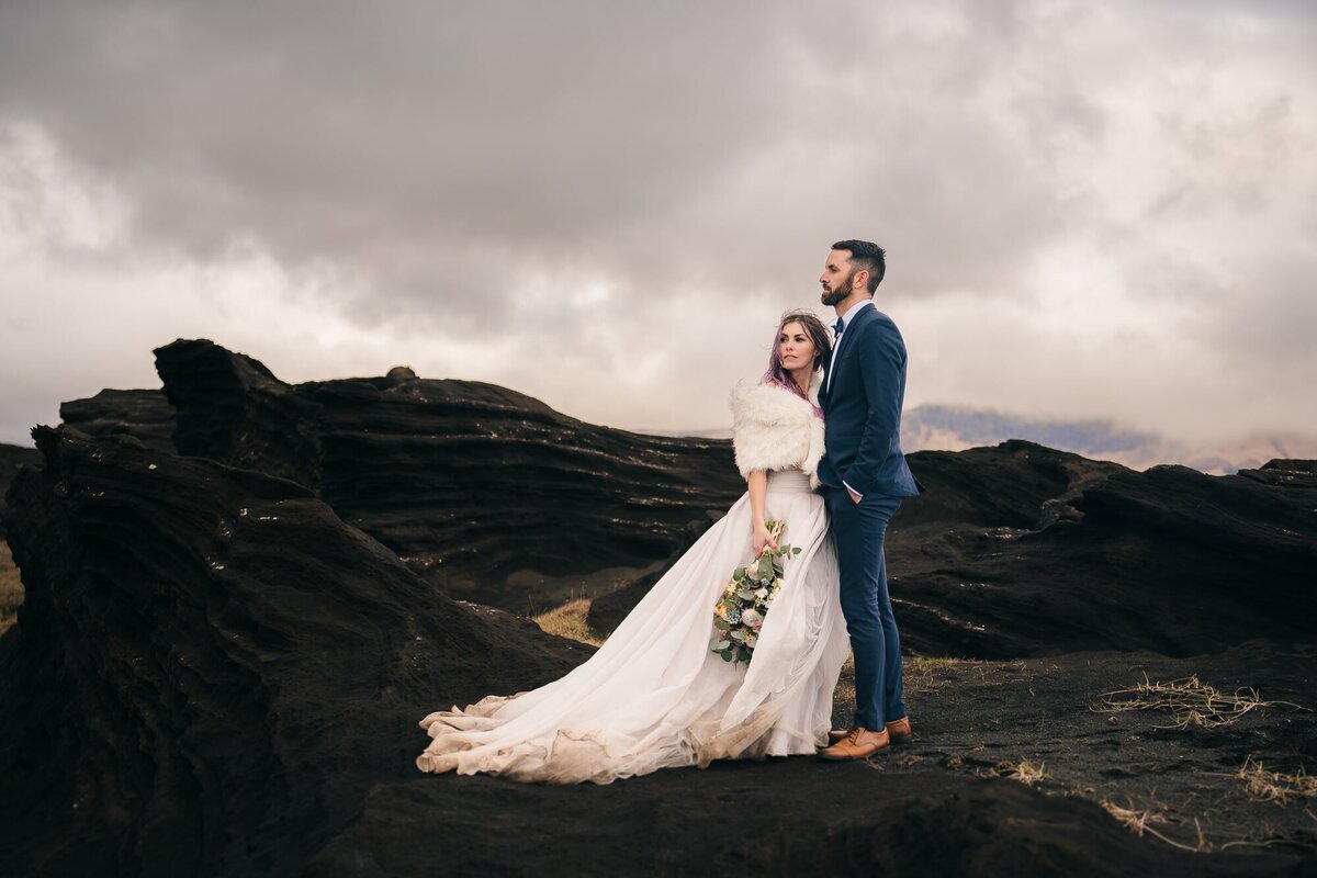 An epic elopement photo of a beautiful couple in Iceland, surrounded by dramatic rocky formations, creating a stunning and unforgettable scene.