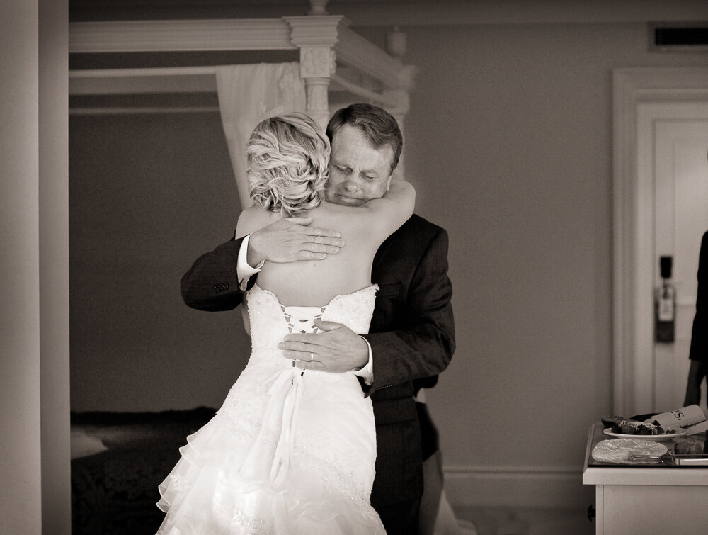 Father of the bride hugging his daughter who is wearing a corset style wedding dress in the bridal suite of the Muckross Park Hotel
