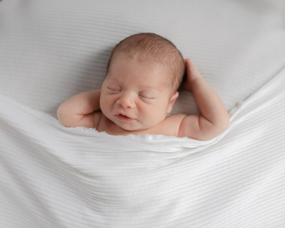 sleeping newborn on white sheets