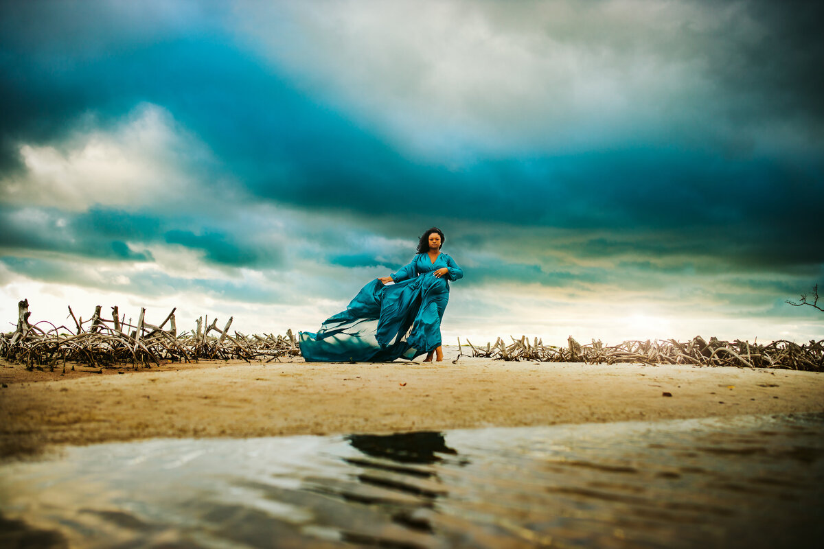 maternity portraits with long flowy gowns, and stormy moody skies at sunset at the beach in tampa bay fl