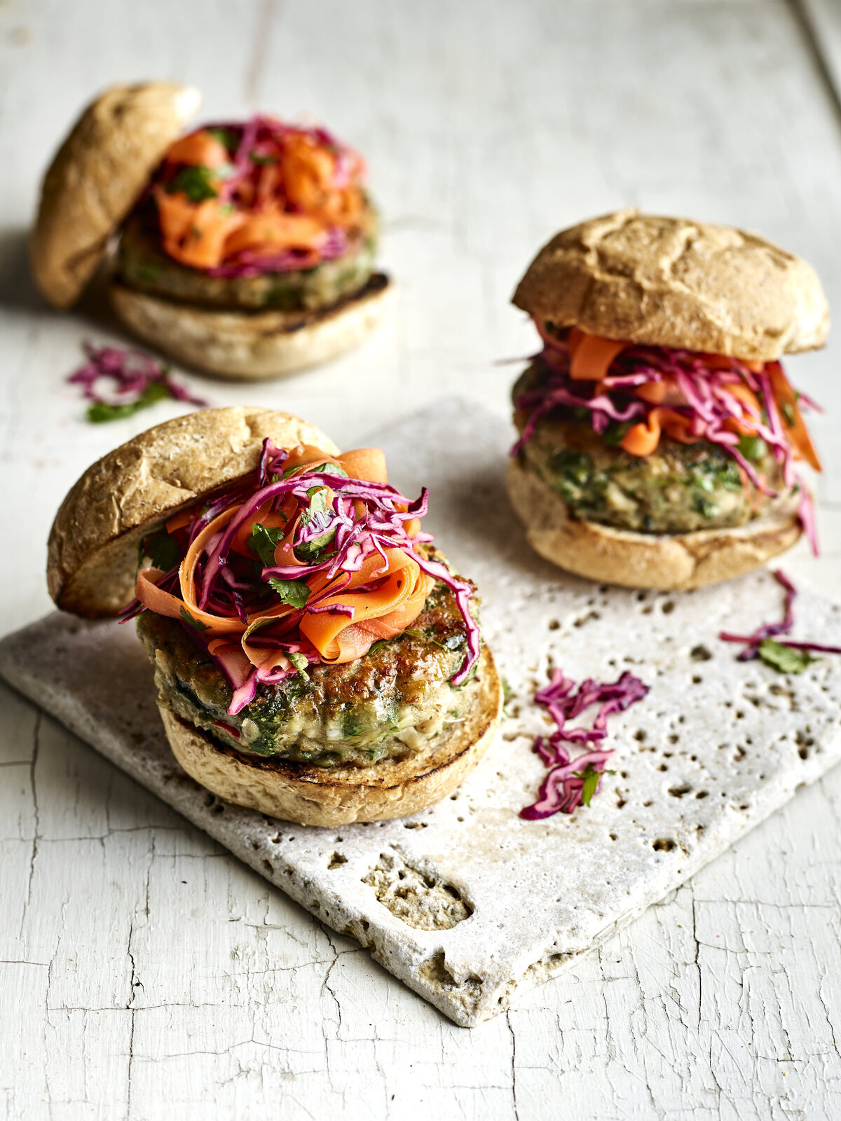 Three lamb burgers with melted cheese and slaw.