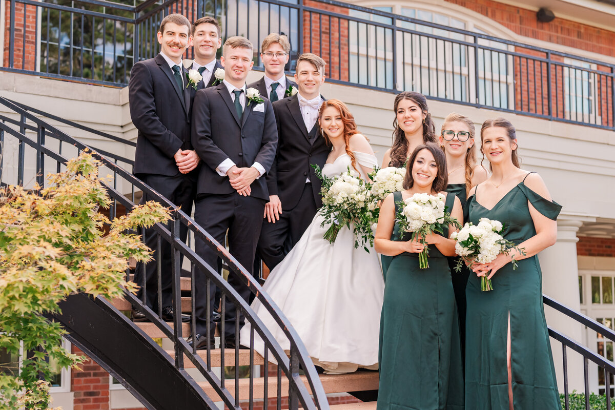 A wedding party cascading down a staircase in Cary on a fall wedding day enjoying their Raleigh wedding photos by JoLynn Photography