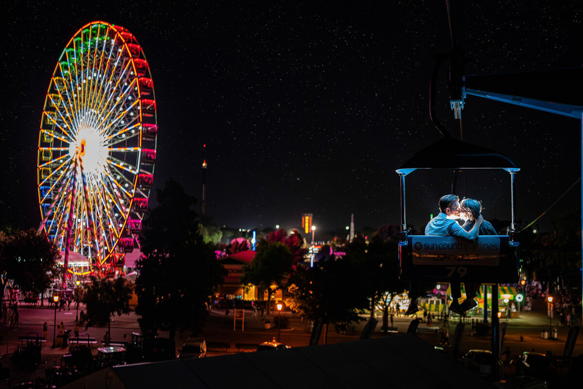 Couple kisses in the glider at the Minnesota State Fair at night.