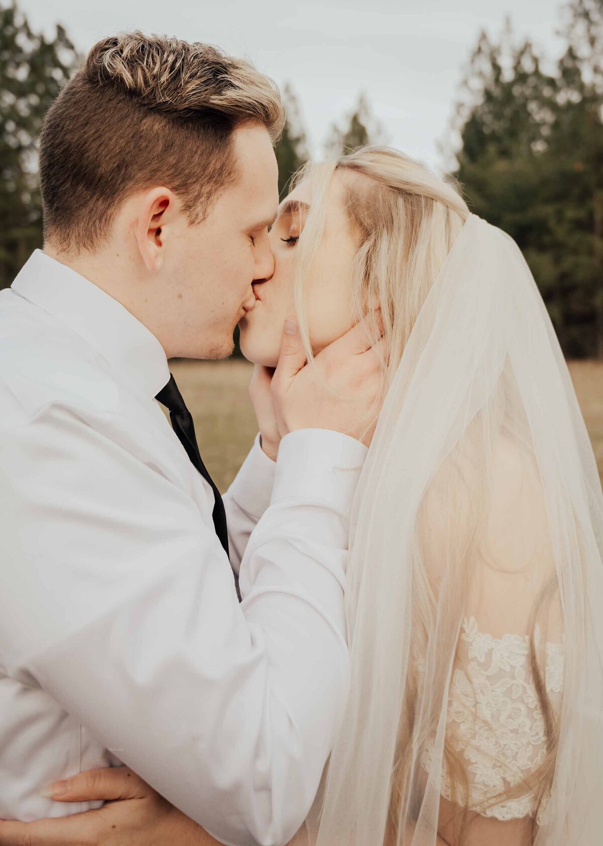Maddie Rae Photography close up of bride and groom kissing. his hands are on her face and her hands are on his waist