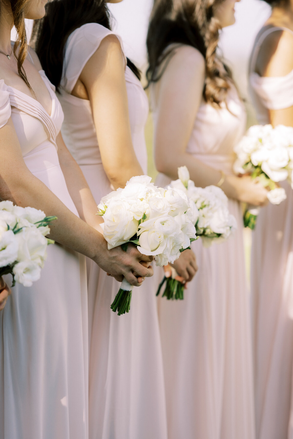 A row of white rose bouquet for the bridesmaids add a special glow of beauty.