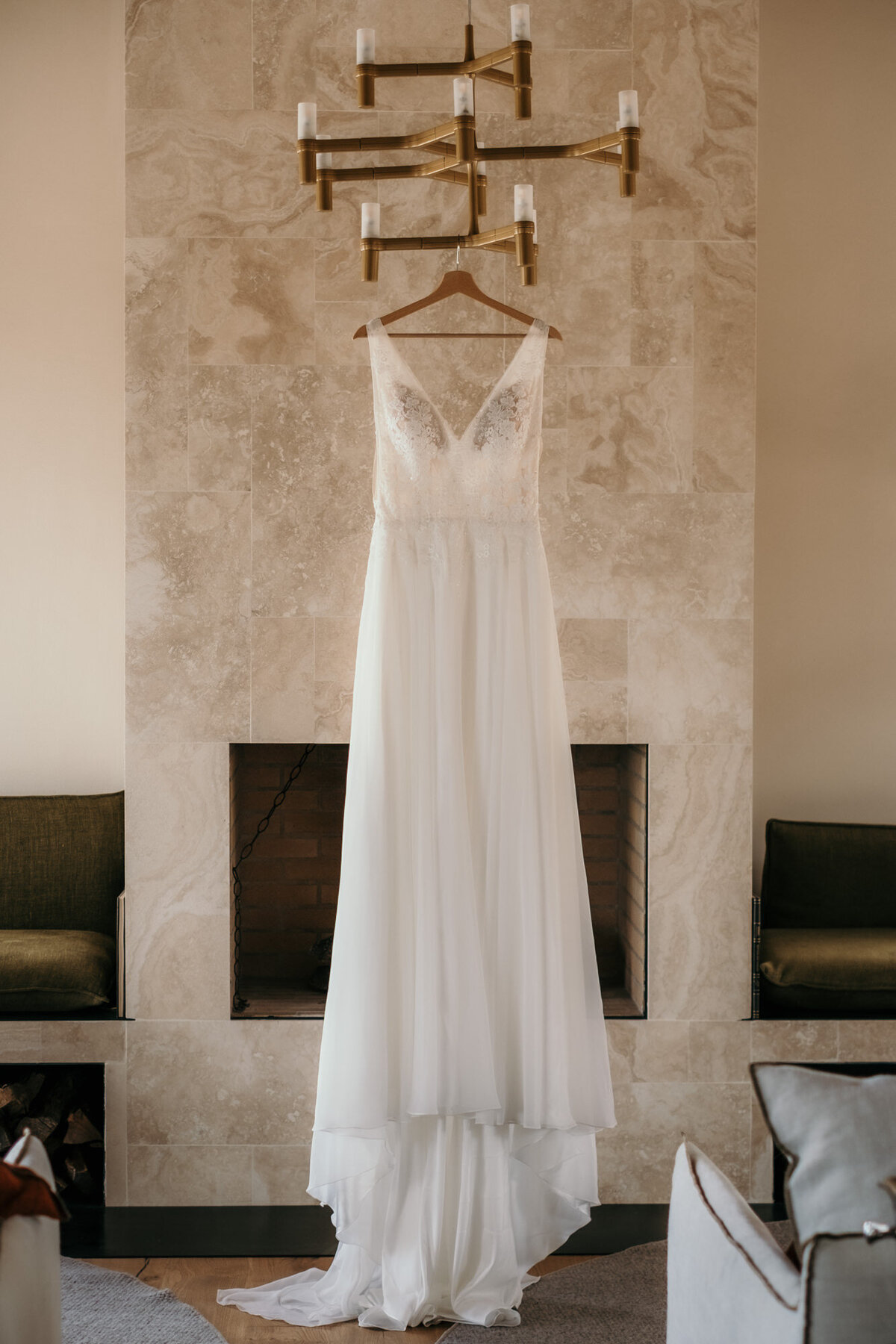 Das Brautkleid hängt an einem modernen Kronleuchter am Kleiderbügel bereit.