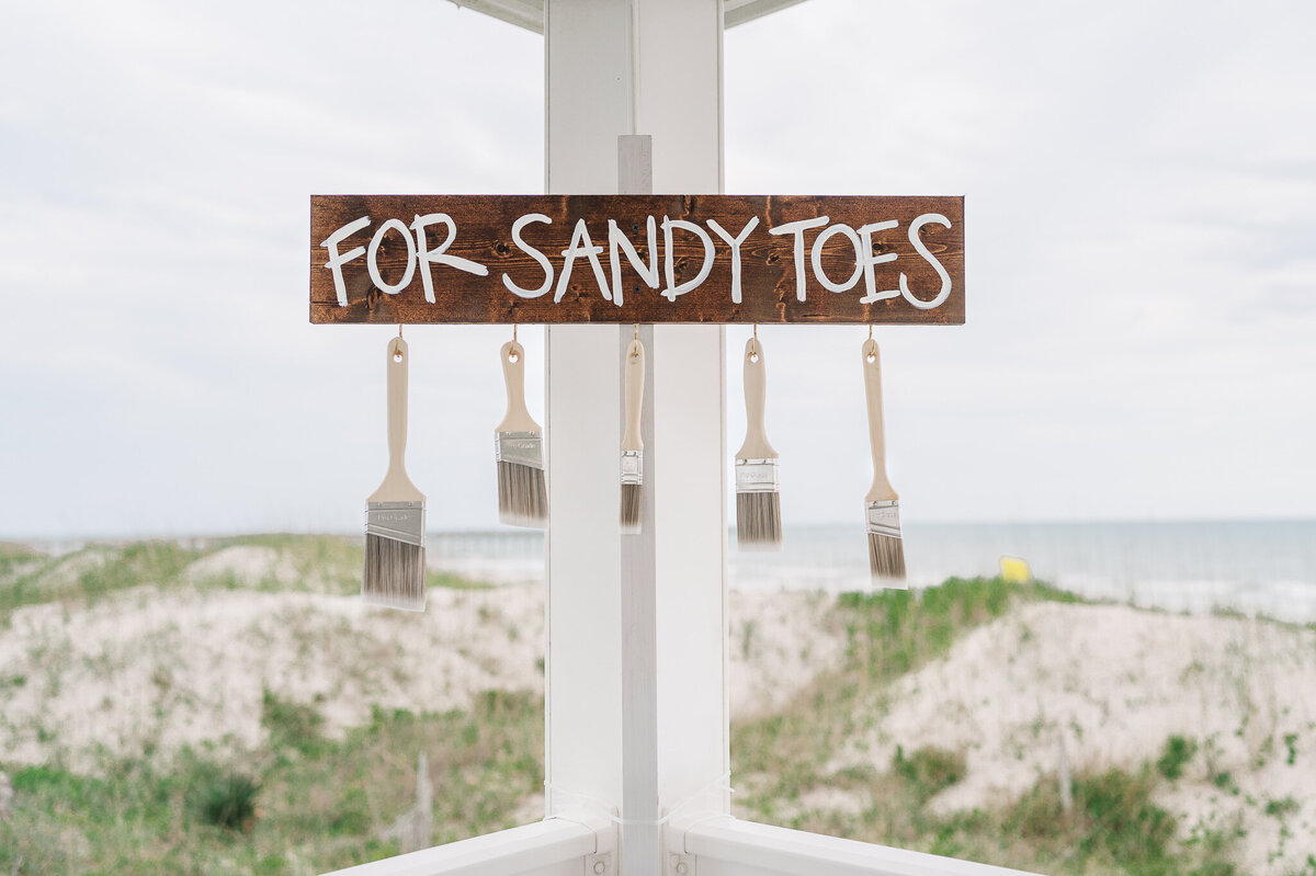 A beach wedding sign for removing sand for Wilmington wedding guests by JoLynn Photography, a Wilmington wedding photographer