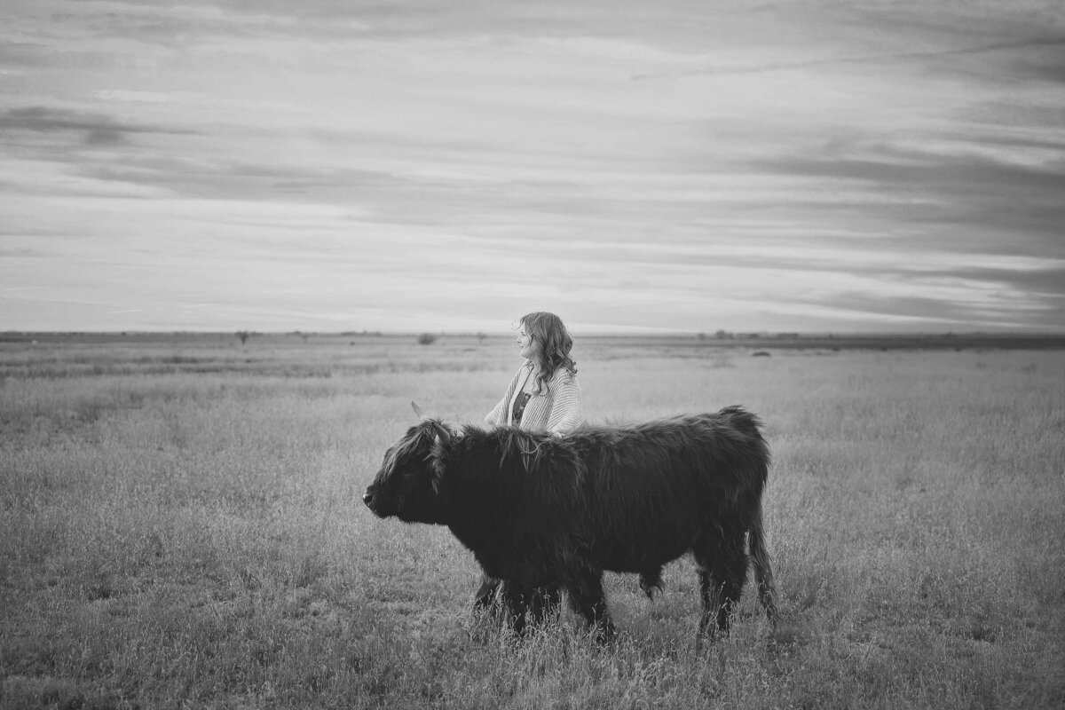 Senior girl standing field with mini highland cow
