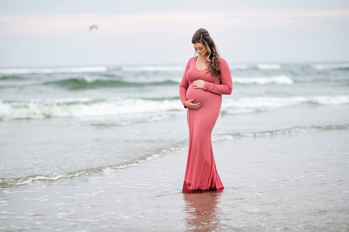 Woman posing in a long pink dress for a maternity session in New Jersey