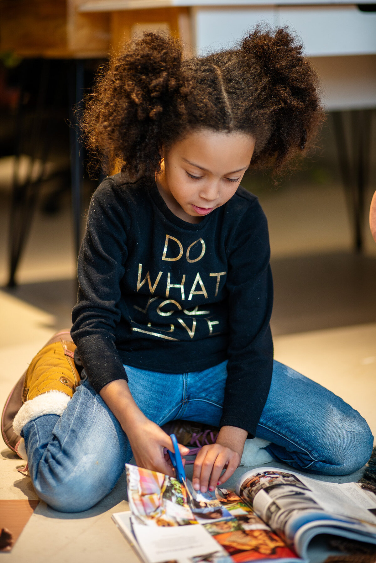 A young child cutting out images in a magazine for their collage