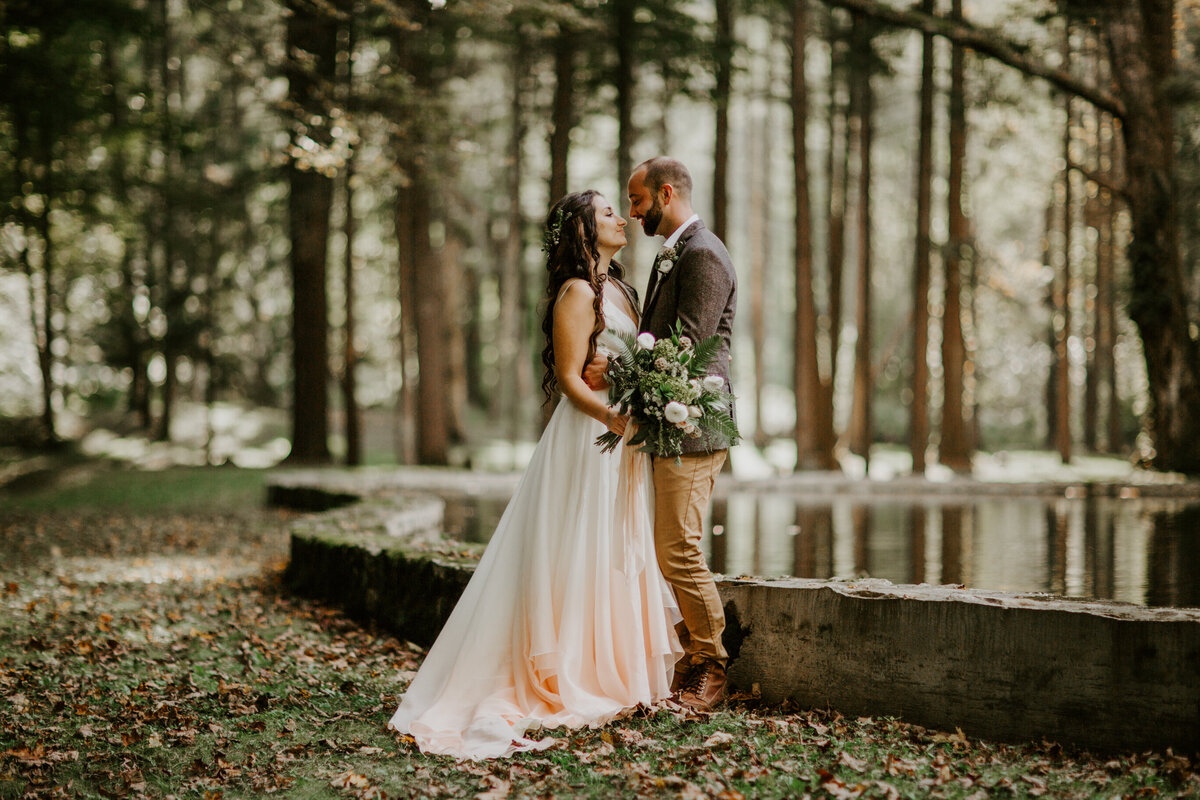 Bride and groom pose in New England forest