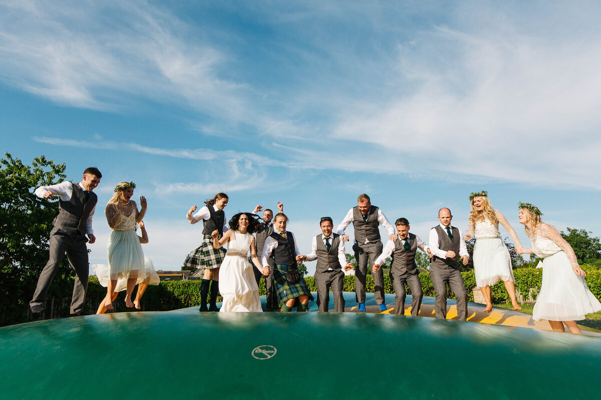 All the bridal party jumping together on the jumping pillow at York Maze