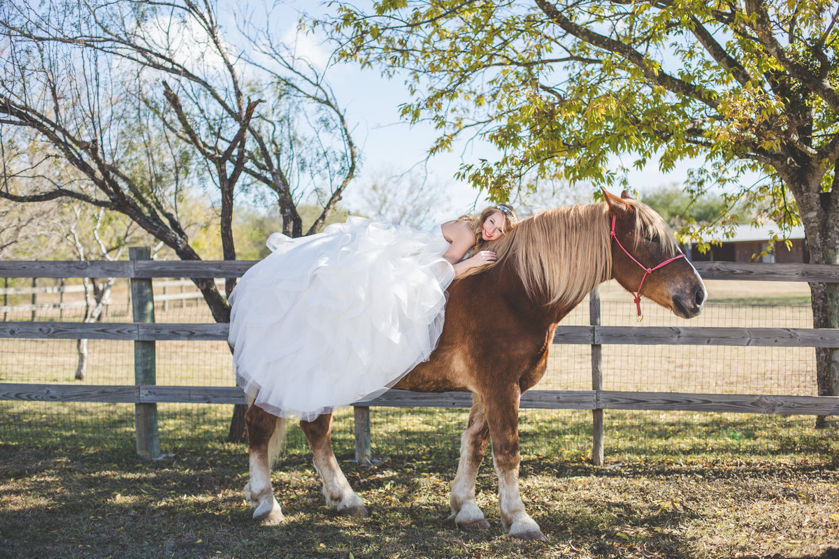 Bride laying on a horse in a field by San Antonio Wedding photographer Expose The Heart