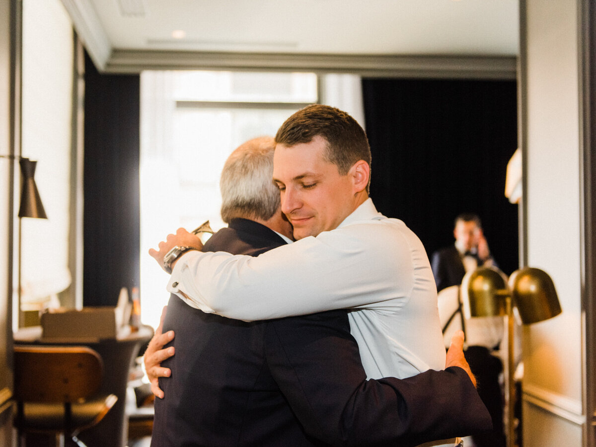 A groom hugs his father during an emotional moment on his wedding day