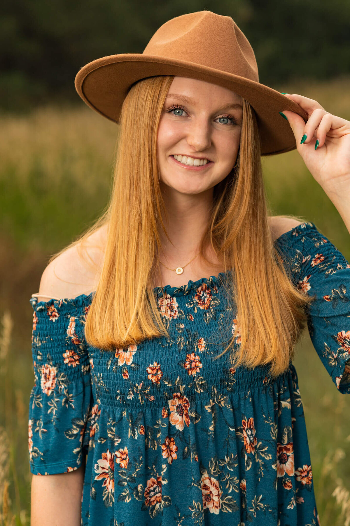 high school senior girl smiling holding her hat