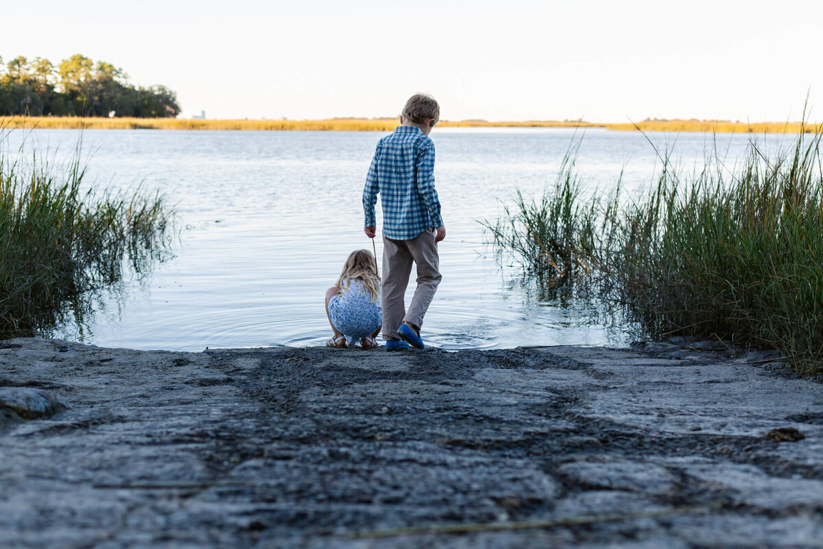 Two children playing on the bank of a salt marsh
