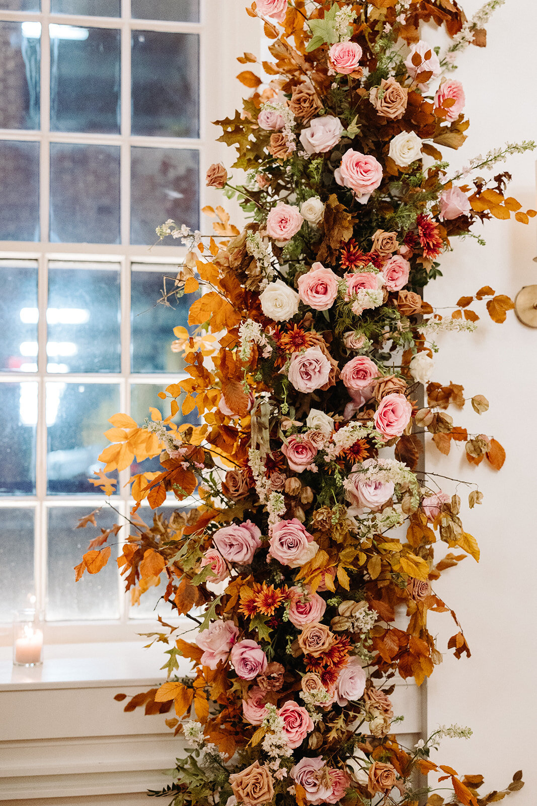 Artful asymmetrical floral wedding ceremony backdrop sets the autumnal hues of mauve, dusty rose, burgundy, terra cotta, and copper florals composed of roses, copper beech, delphinium, raintree pods, mums, and fall foliage. Design by Rosemary and Finch in Nashville, TN.