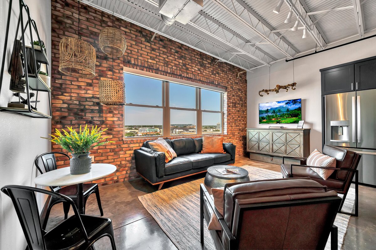 Industrial modern living room with exposed brick in this one-bedroom, one-bathroom luxury condo in the historic Behrens building in downtown Waco, TX.