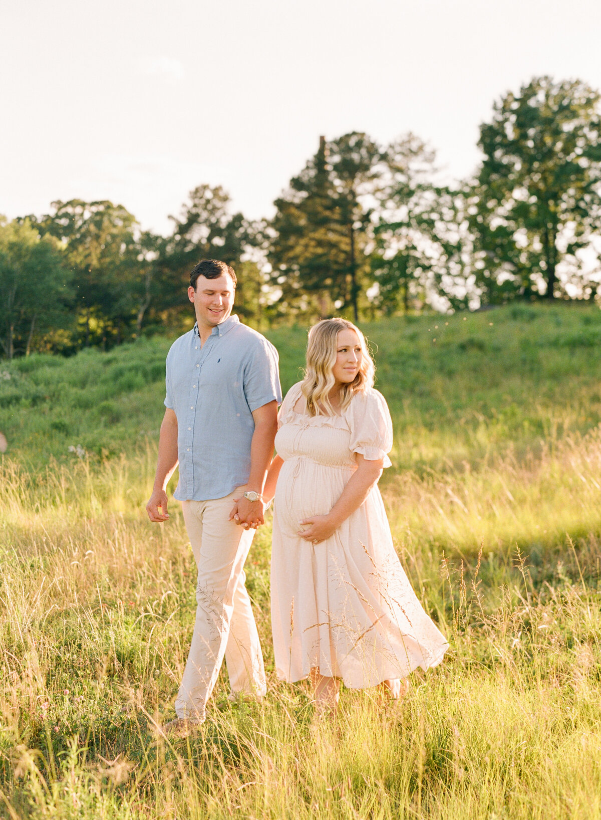 Couple walks in a field during their maternity session at the Art Museum in Raleigh NC. Photographed by Raleigh Maternity Photographer A.J. Dunlap Photography.