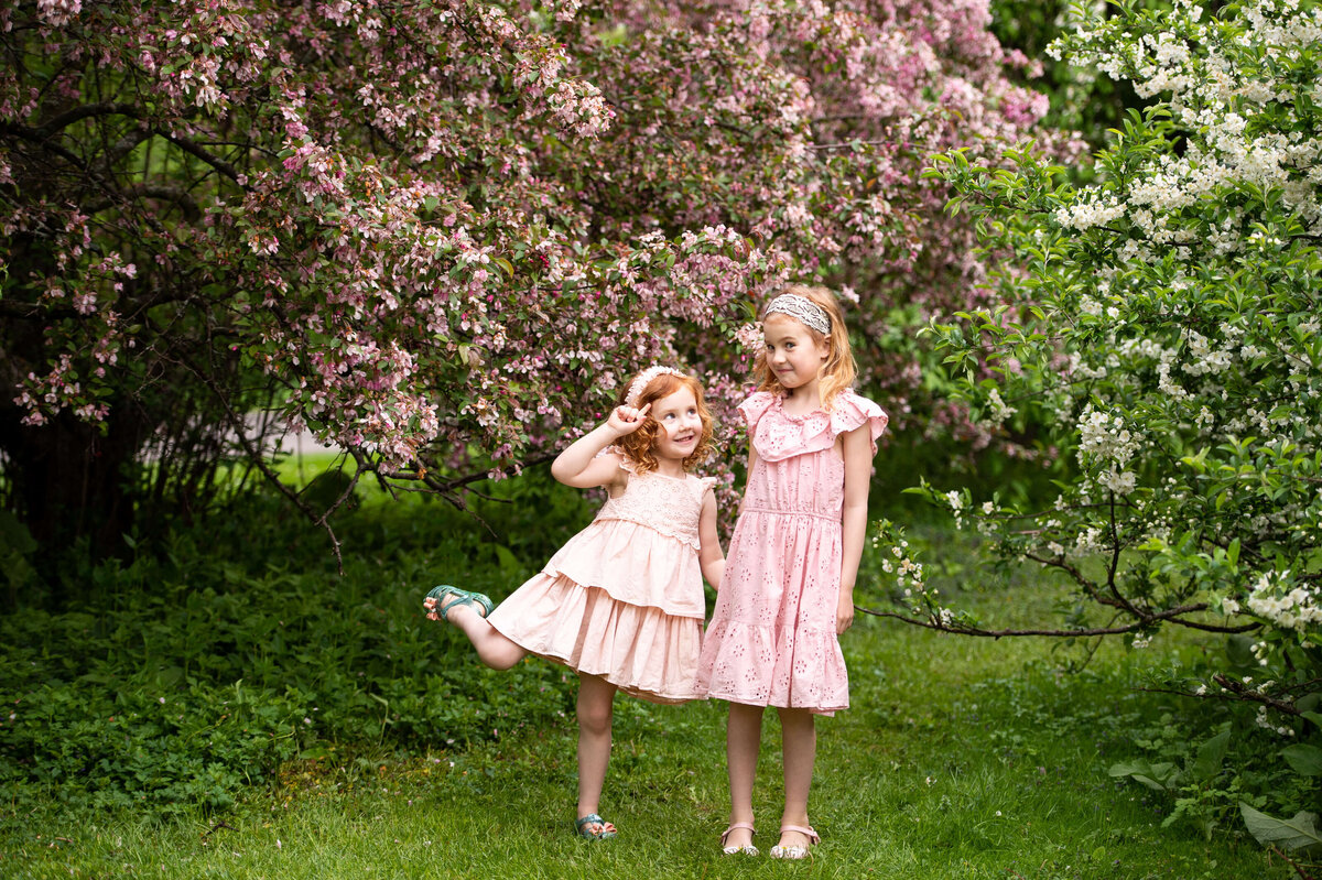 two little girls with red hair and pink dresses show their playful personalities during their family photos in Ottawa Arboretum