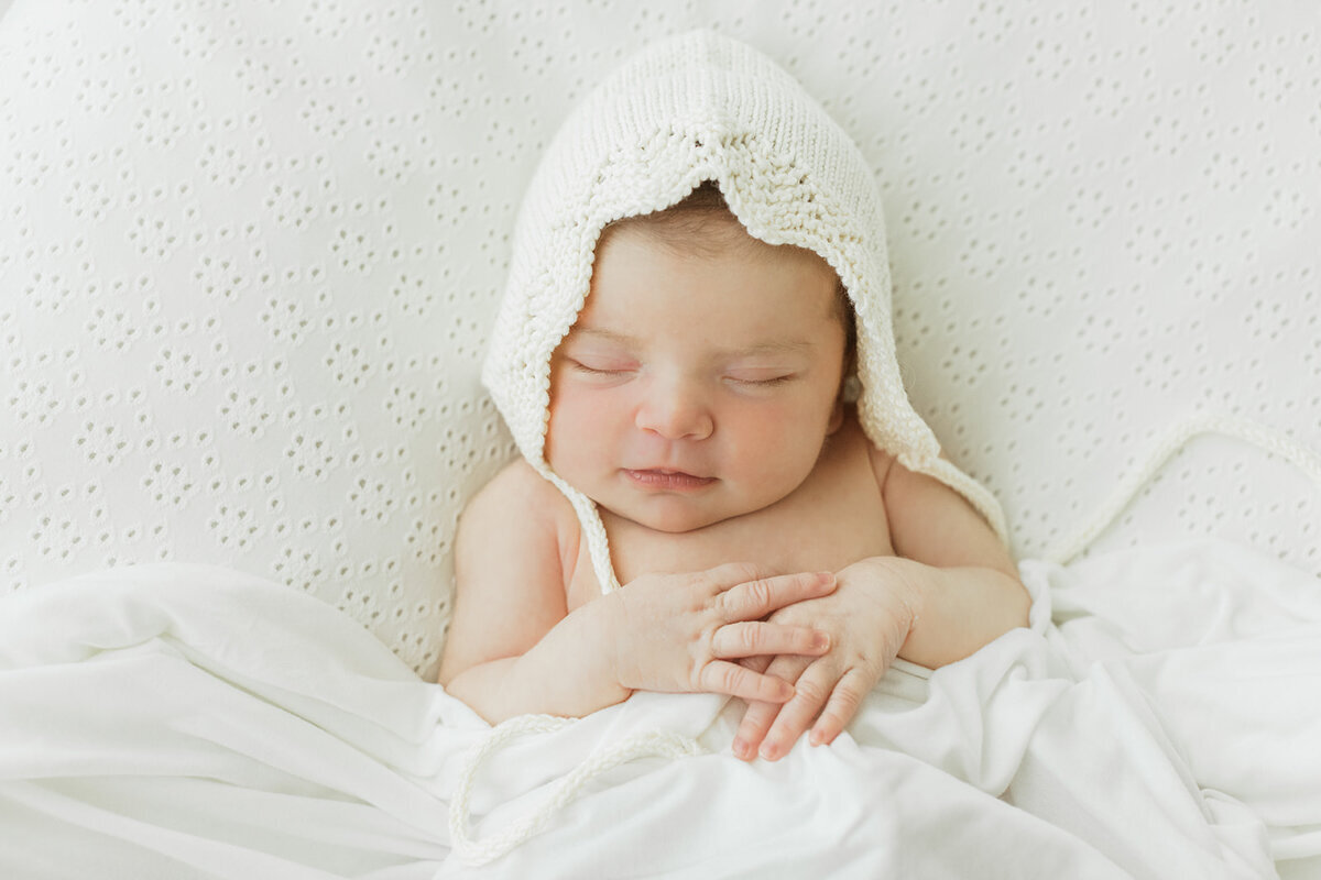 newborn baby girl sleeps while wearing and heirloom bonnet
