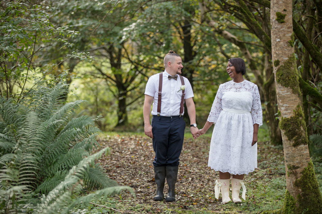 Bride in wellington boots holding hands with groom at elopement wedding The Green Cornwall