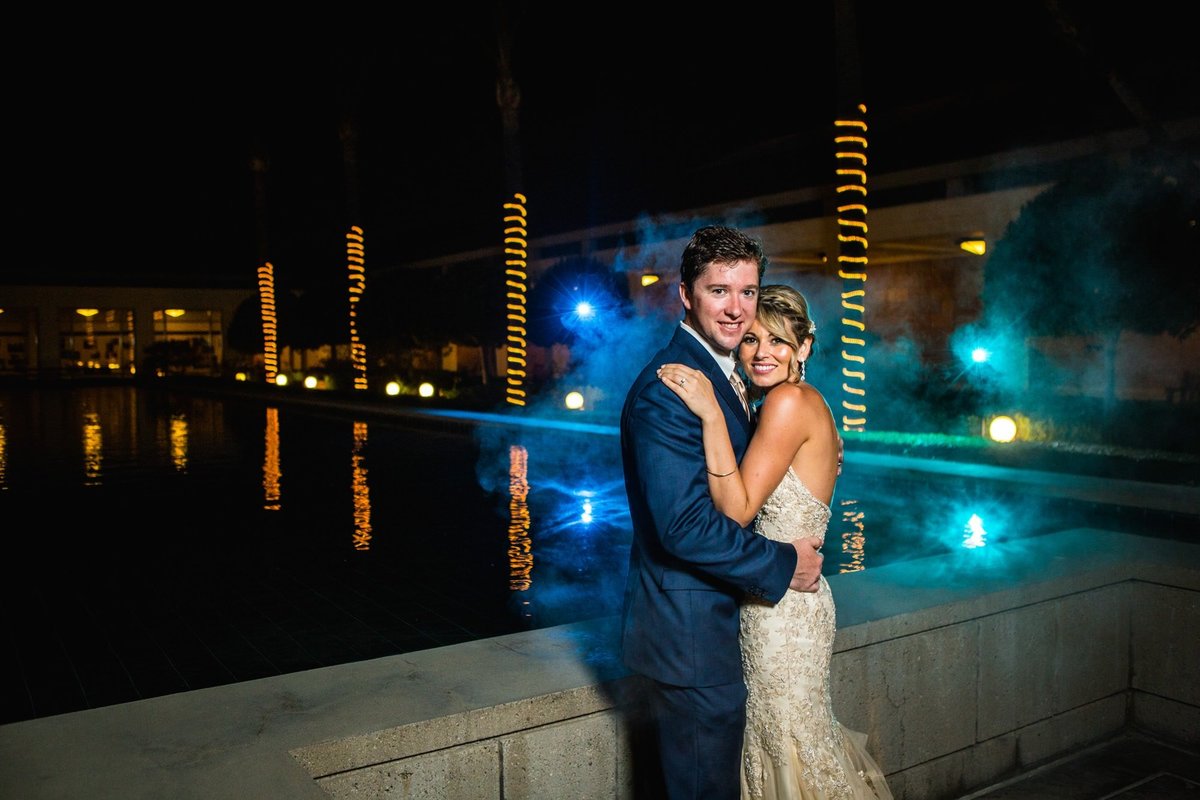 Bride and Groom embrace for a night shot at the Richard Nixon Library with colored lighting in the background