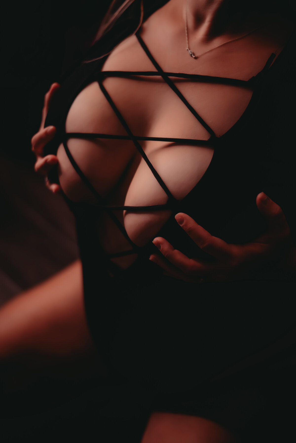 woman holding her breasts in black bodysuit