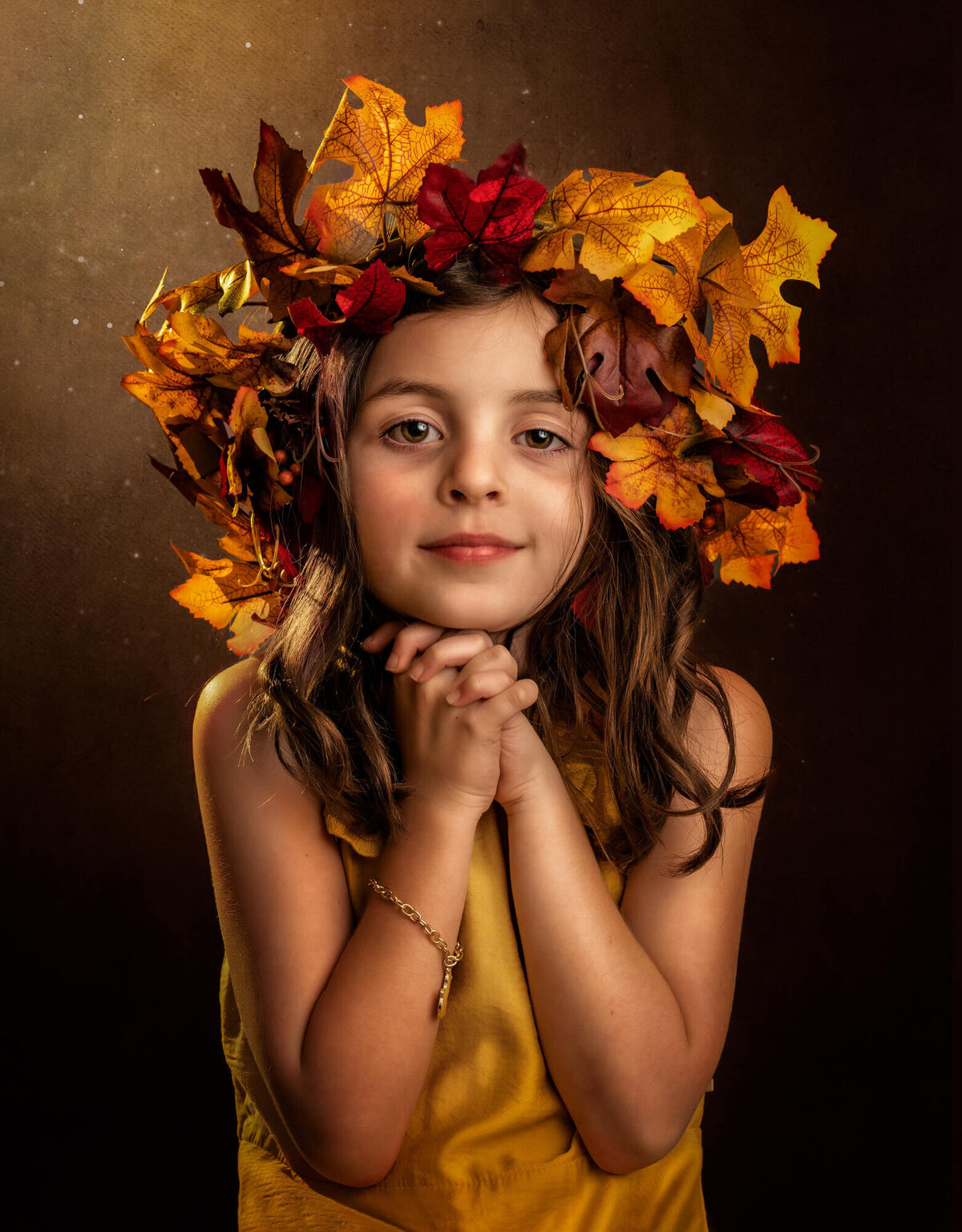 A beautiful young girl in a yellow dress with a yellow leaf crown in her hair