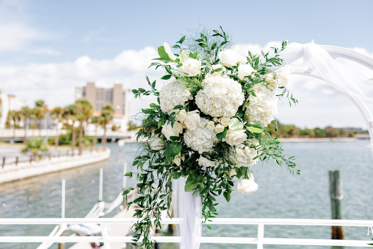 Elegant wedding bouquet with white roses and blue floral accents on yacht railing.