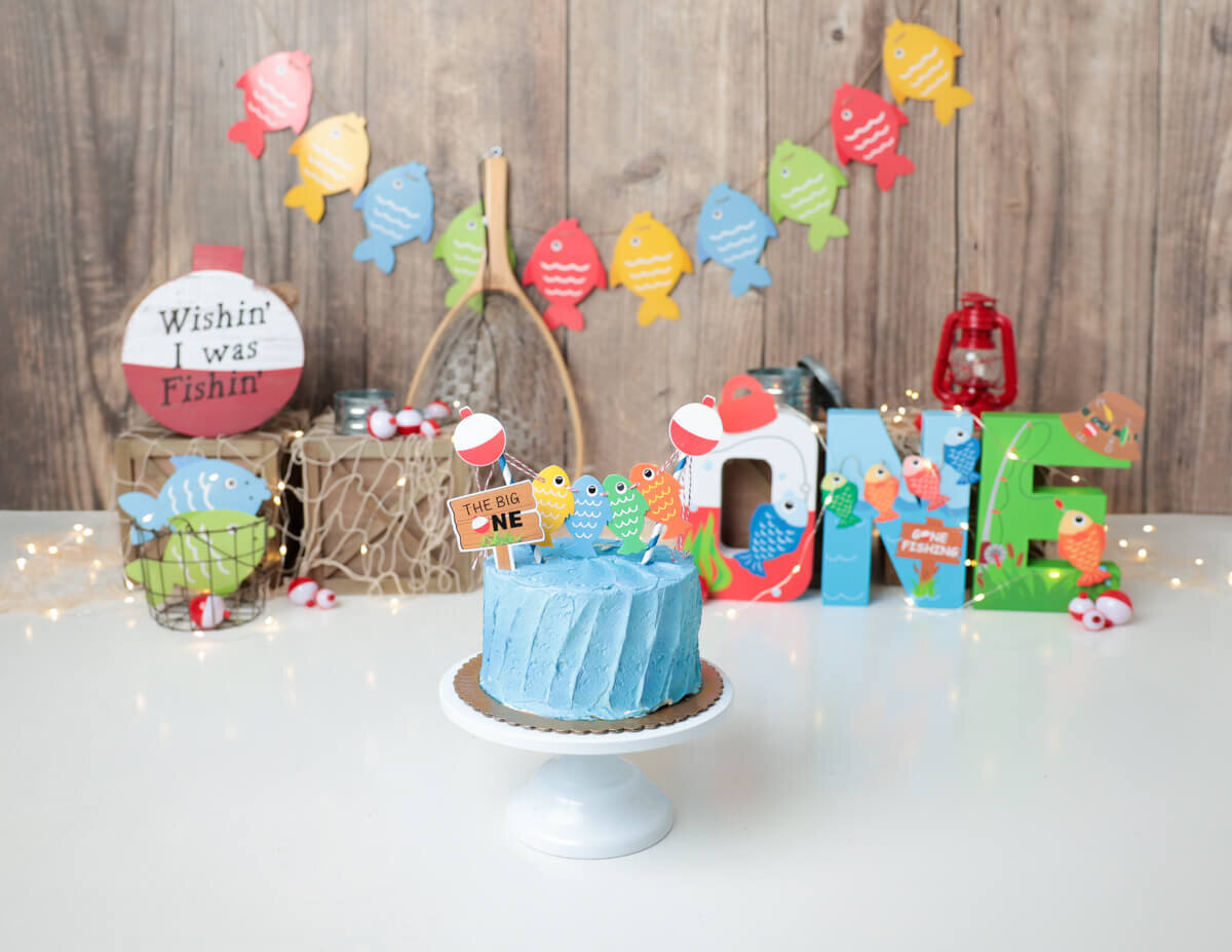 Creative setup featuring a fishing-themed cake and props for a custom cake smash in Rochester, NY.