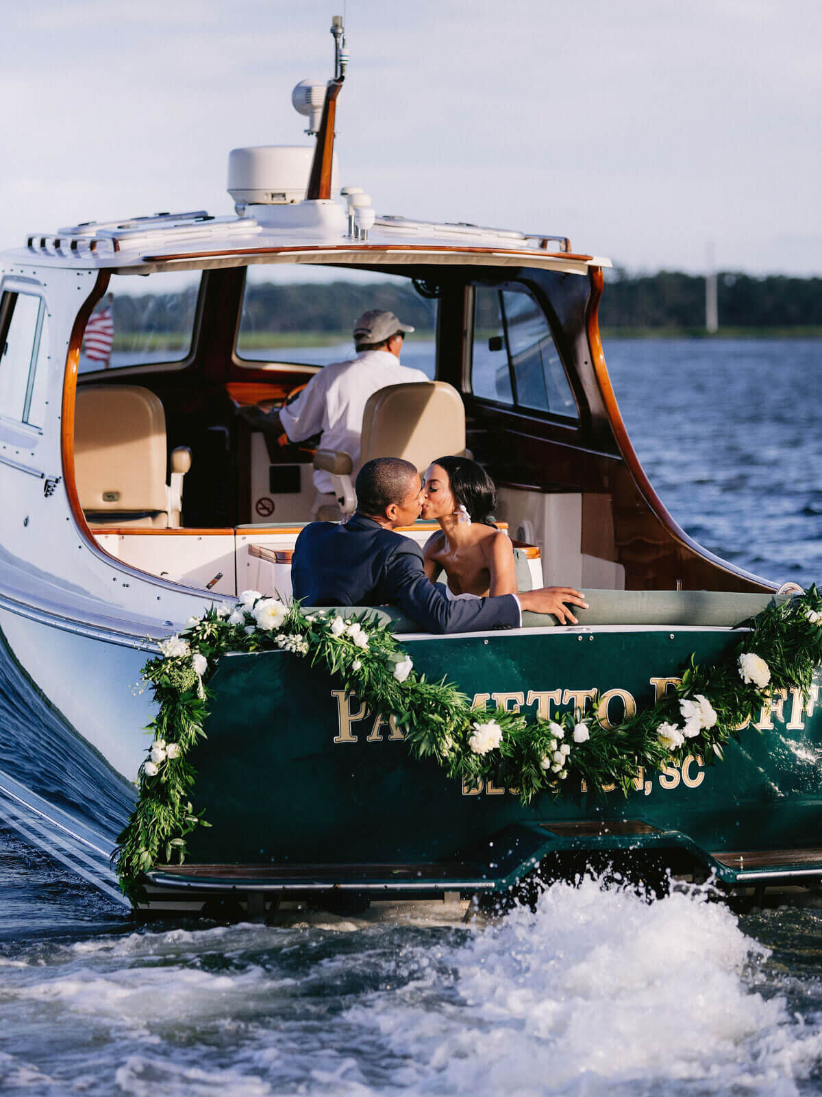 The bride and groom are kissing inside a moving yacht in Montage at Palmetto Bluff. Destination wedding image by Jenny Fu Studio