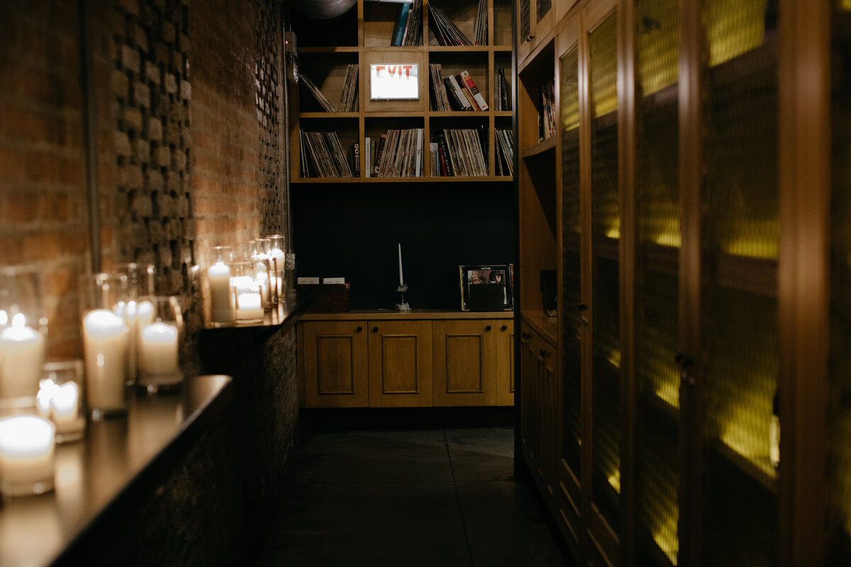 Hallway of Ada Restaurant dimly lit with candles illuminating brick walls