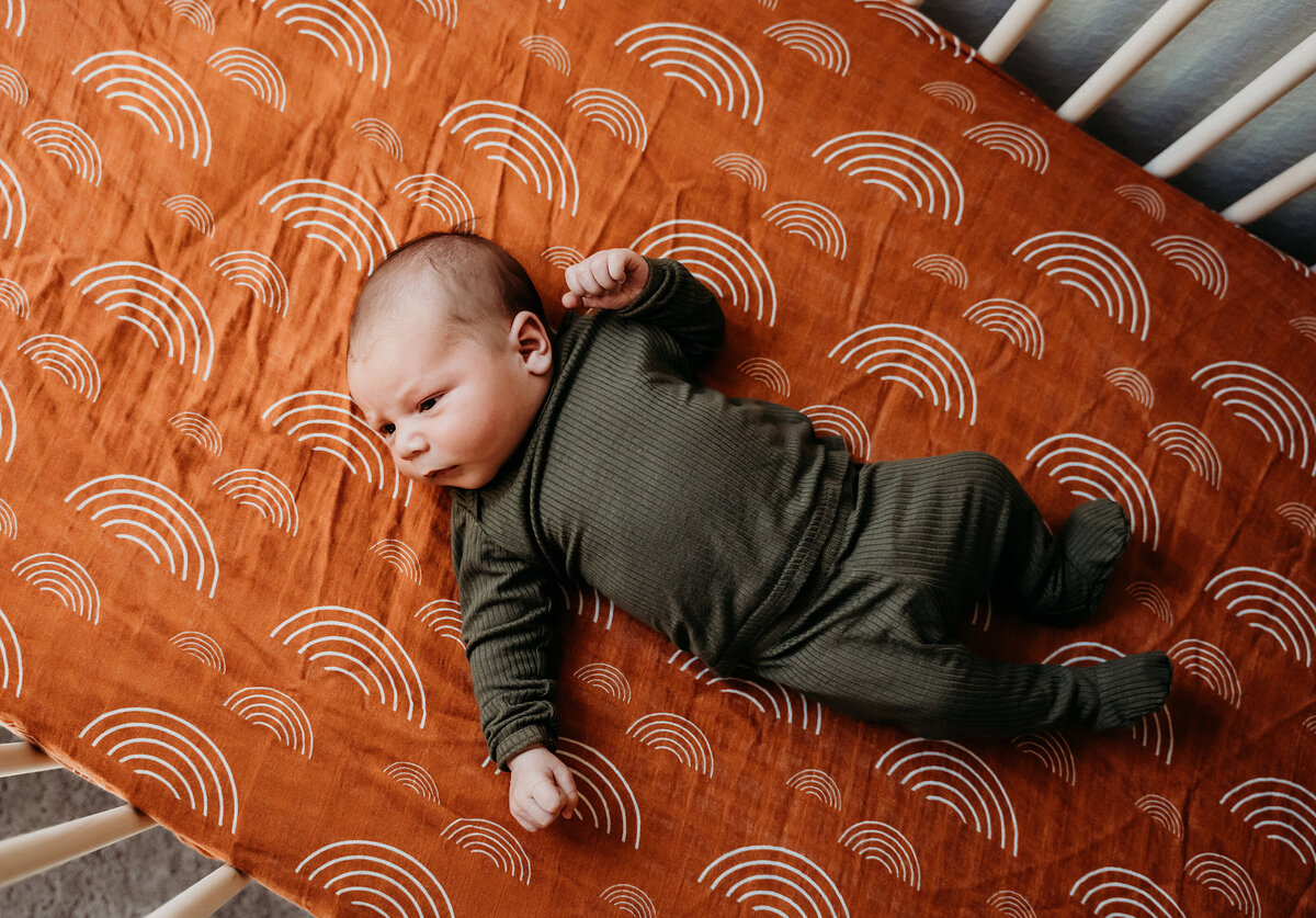 Newborn Photographer,  a baby lays awake in his crib
