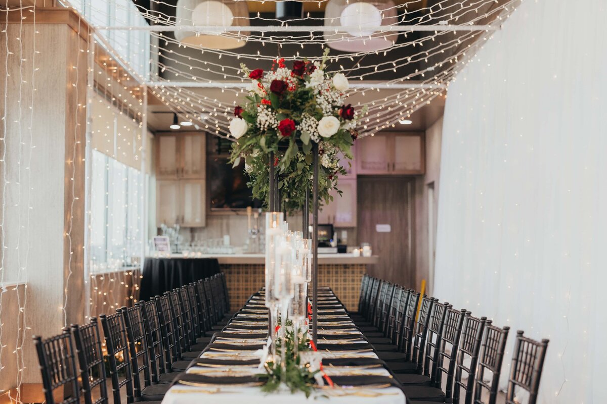 Elegant banquet hall decorated with fairy lights above and a long table set with flowers, candles, and dinnerware for park farm winery weddings.