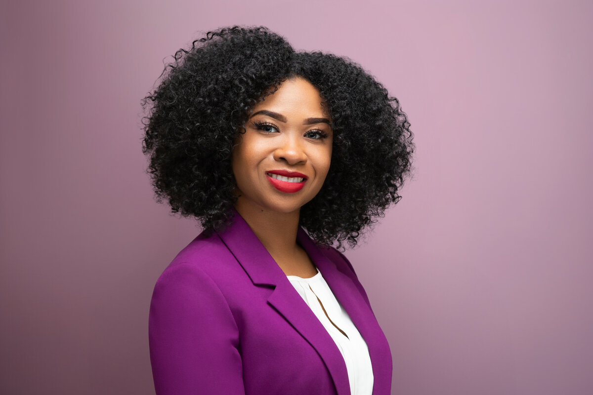 An African American black professional woman in a pink blazer poses for a headshot on a grey background in Cincinnati Ohio Studio