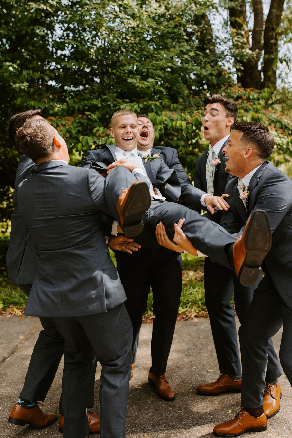 groomsmen smiling and holding up the groom together